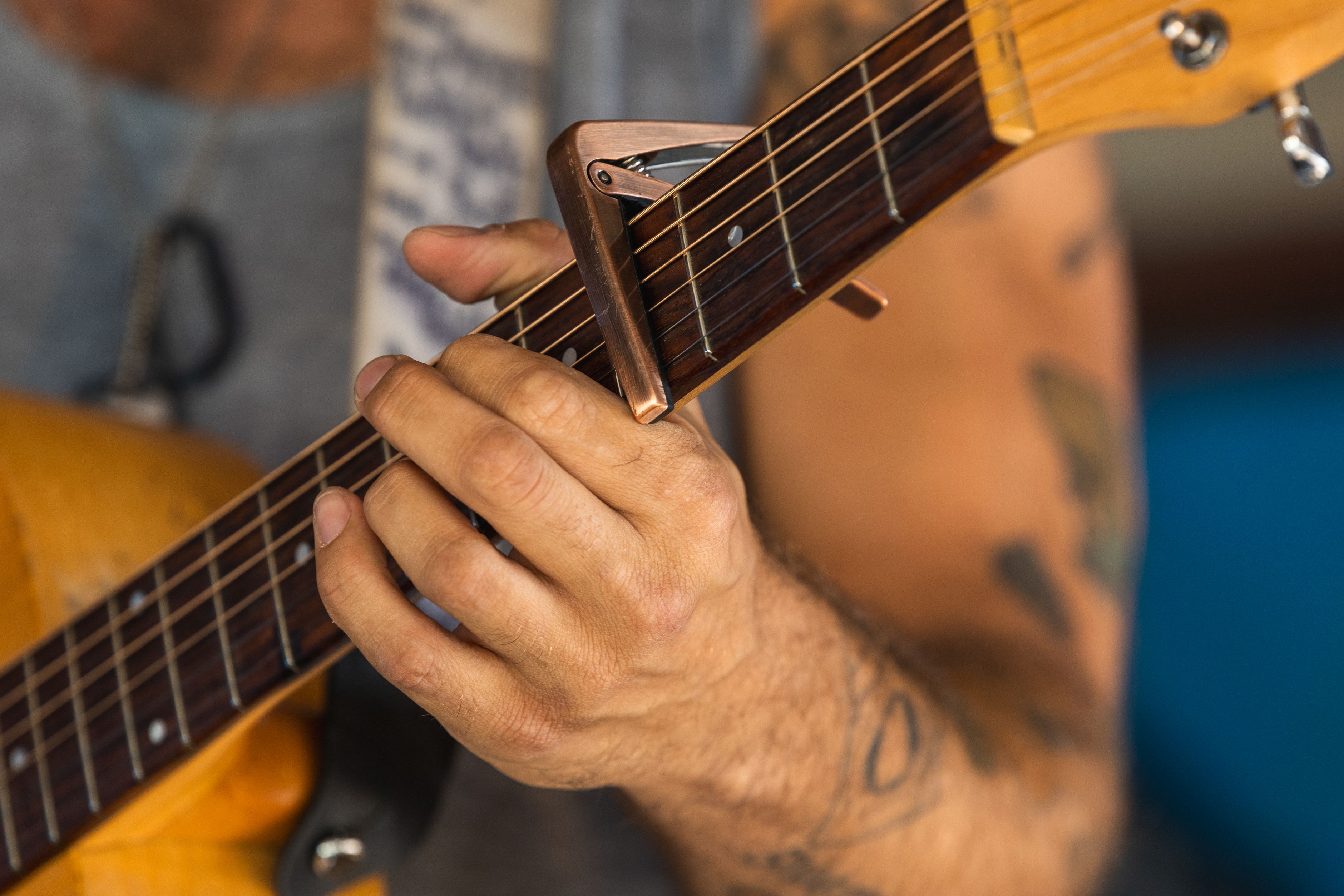 Gros plan sur la main d'un guitariste utilisant un capodastre sur une guitare acoustique
