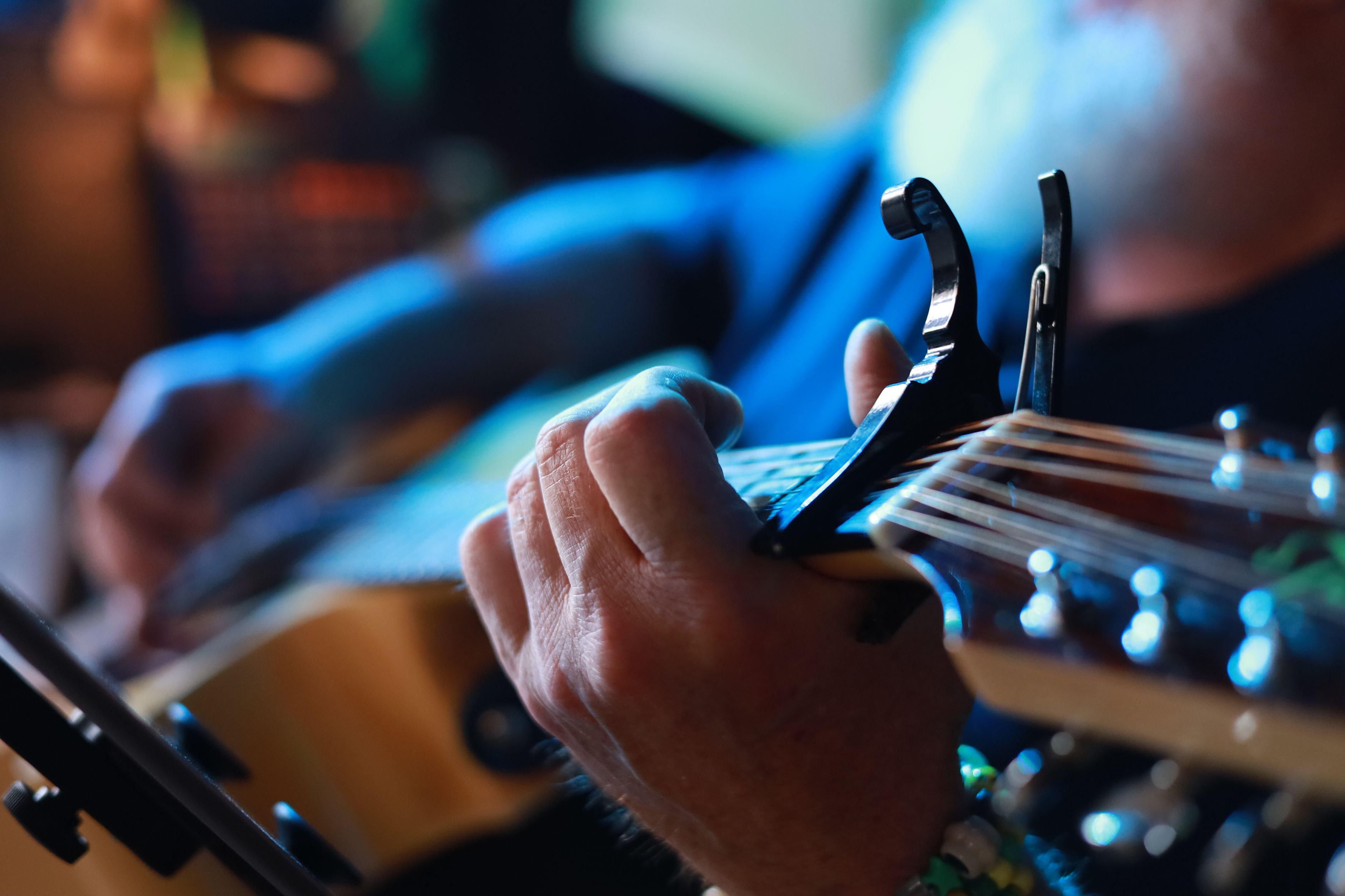 Vue détaillée des mains d'un guitariste plaçant un capodastre sur le manche
